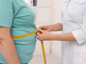 "رجل يحمل محيط خصره ويقيس الضغط – يرمز إلى متلازمة التمثيل الغذائي