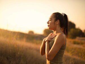 Calm woman practicing breathwork meditation at home with eyes closed and hands on her belly—illustrating natural breathwork for stress relief and relaxation.