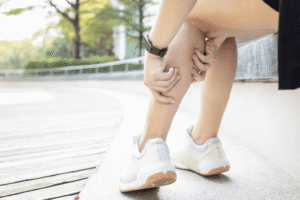 Person holding a painful calf, illustrating leg muscle ache while taking a cholesterol‑lowering drug (statin).